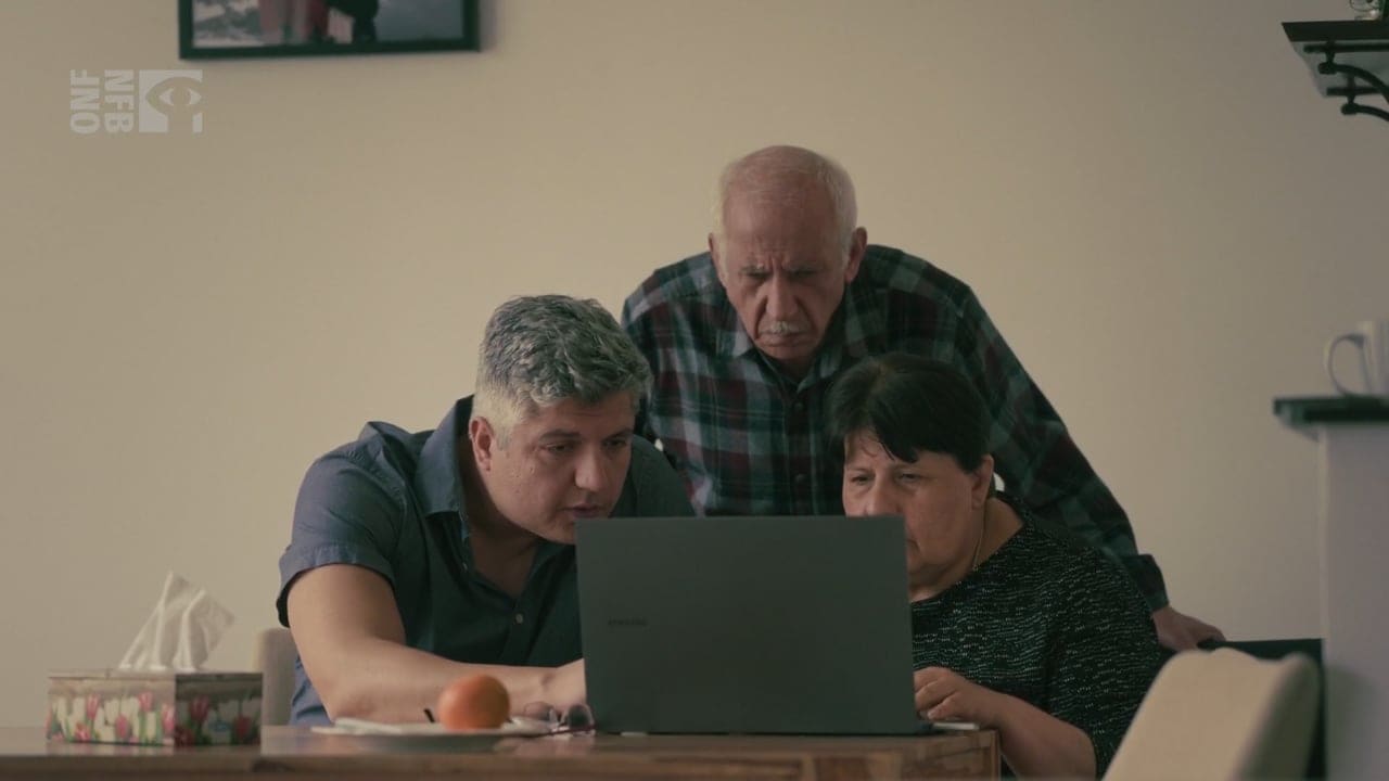 Armin Morattab and his parents look at a laptop together at a kitchen table.